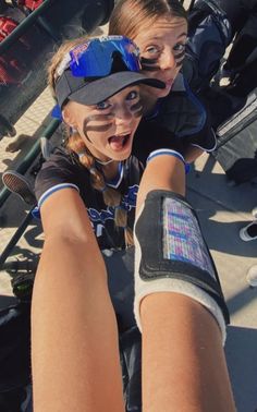 two girls with their arms wrapped around each other in baseball gloves and visors