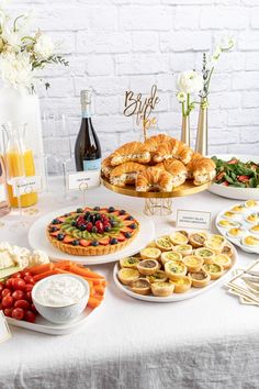 a table topped with pies, fruit and pastries next to bottles of wine