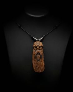 a necklace made out of wood with a wooden face on the front and black cord