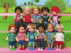 a group of children's dolls are posed together on a pink bench in front of a colorful background