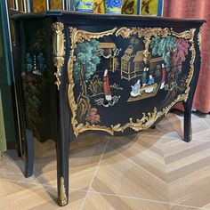 an ornate black and gold painted cabinet on display