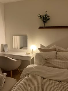 a white bed sitting next to a desk with a lamp on it's side