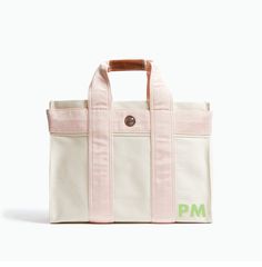 a pink and white tote bag with the word pm printed in green on it