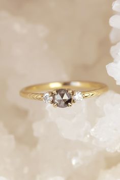 three stone ring sitting on top of white flowers in front of a light colored background