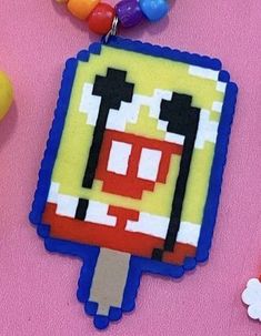 an ice cream lolly pop keychain on a pink surface next to candy