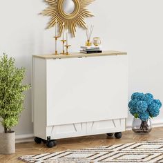 a white cabinet sitting on top of a wooden floor next to a potted plant