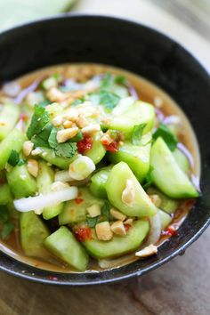 a bowl filled with cucumbers, onions and other vegetables on top of a wooden table