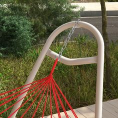 a red and white hammock hanging from a metal pole on a wooden deck