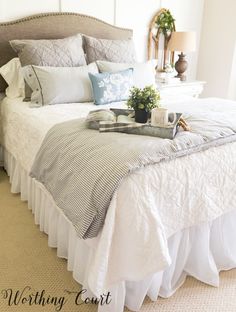 a white bed topped with lots of pillows and blankets