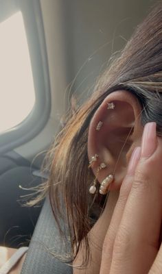 a woman is holding her ear up to the side of her head while sitting in an airplane