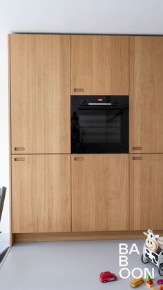 an oven built into the side of a wooden cabinet in a room with toys on the floor