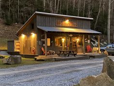 there is a small cabin in the woods with lights on and two people standing outside