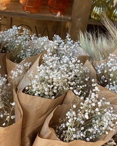 several bags filled with white flowers sitting on top of a wooden table next to plants