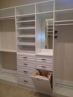 an empty closet with white drawers and shelves