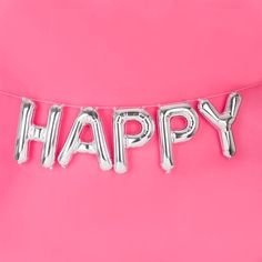 the word happy spelled out in silver foil on a pink background with an air balloon