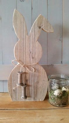 a wooden bunny statue sitting on top of a table next to a jar filled with rocks