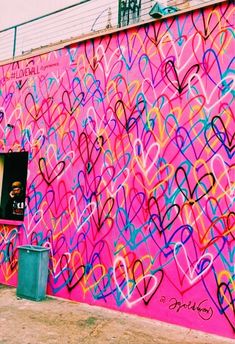 a pink wall with lots of hearts painted on it and a man looking out the window