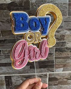 a hand holding up a cake topper with the words boy or girl on it