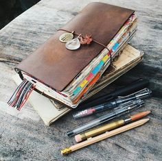 an open notebook with coins and pens sitting on top of it next to other items