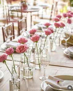 a long table is set with pink flowers in glass vases