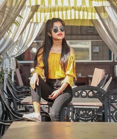 a woman sitting on top of a wooden table under a yellow and white awning