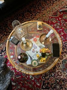 a glass table with two wine glasses on it and flowers in vases sitting on top