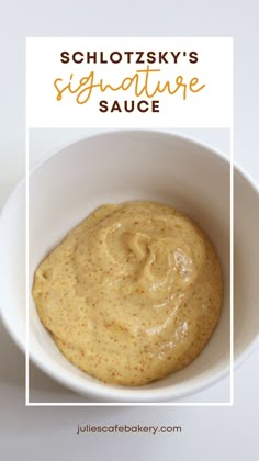 a white bowl filled with yellow sauce on top of a table next to a spoon