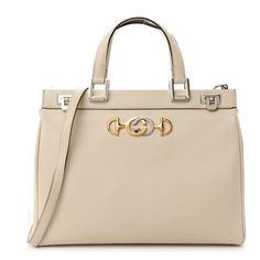 This is an authentic GUCCI Grainy Calfskin Medium Zumi Top Handle Bag in Mystic White. This shoulder bagis crafted of grainy calfskin leather in white. This bag features leather top handles and an optional leather shoulder strap with silver hardware. The front features an interlocking G Horsebit logo in silver and gold, with a hinged lock on each side for a secure closure. This opens to a partitioned burgundy leather interior with zipper pockets. Luxury White Gucci Shoulder Bag, White Gucci Bag With Handles, High-end White Bag With Top Carry Handle, Luxury Gucci Shoulder Bag With Silver-tone Hardware, Soho Disco Bag, Gucci Double Handle Bags With Gold-tone Hardware, Gucci Crossbody Bag, Gucci Crossbody, Gucci Shoulder Bag