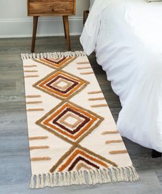 a bedroom with a bed, nightstand and rugs on the floor in front of it