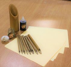 some pens and paper are sitting on the floor next to a bottle with ink in it