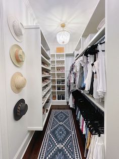 a walk in closet with lots of clothes and hats on the shelves next to it