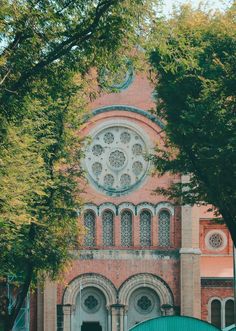 an old building with a clock on it's face and trees in front of it