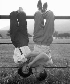 two men doing handstands in front of a fence with their feet on the ground