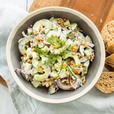 a white bowl filled with cucumber and fennel salad on top of a wooden cutting board