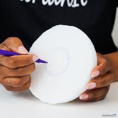 a person holding a white object with a purple pen in their left hand and writing on it