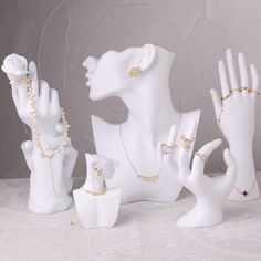 three white ceramic figurines with rings and bracelets