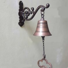 a metal bell with a heart shaped key hanging from it's side on a wall