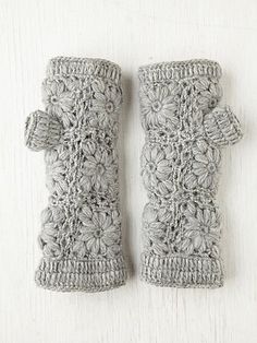 two crocheted gray mittens sitting on top of a white table next to each other