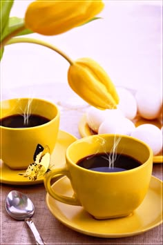 two yellow cups filled with coffee sitting on top of a table