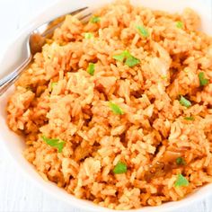 a white bowl filled with rice and topped with chopped green onions next to a fork