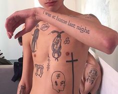 a man with tattoos on his chest pointing at the camera