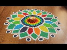 a colorful flower design is on the floor with a candle in it's center