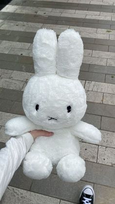 a person holding a white stuffed animal in their hand