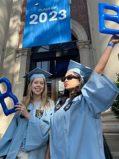 two women in graduation gowns hold up letters that spell out the word class of 203