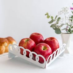 there are some apples in a white tray on the table next to other pastries