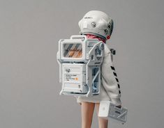 a doll is dressed in an astronaut suit and holding a cell phone to its back