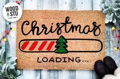 a christmas loading door mat sitting on top of a wooden floor next to a pair of black gloves