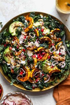 a salad in a bowl with onions, kale and pomegranates