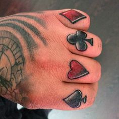 a person with tattoos on their fingers holding a clock and playing card symbols in front of them