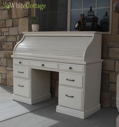 a white desk sitting on top of a porch next to a brick wall and window